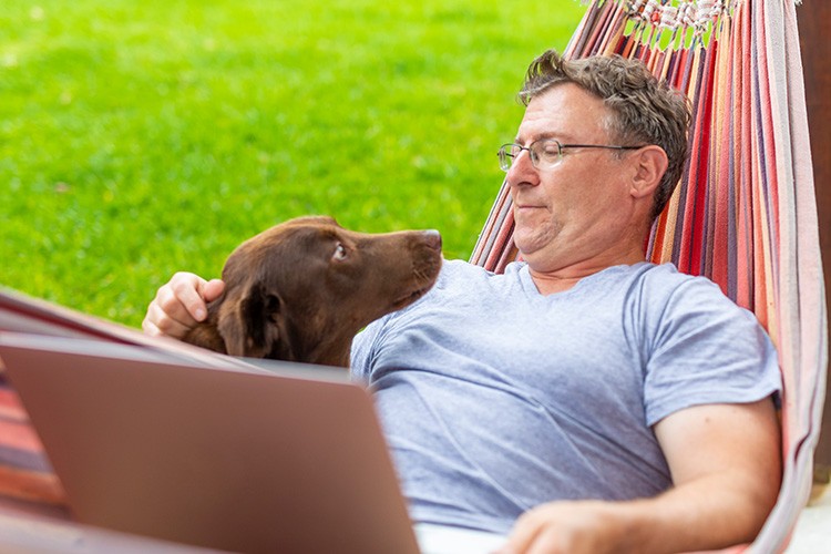 man-in-hammock-with-dog-looking-at-laptop-computer-750x500-1.jpg