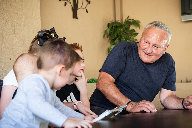 Older man sitting at a table next to three small children