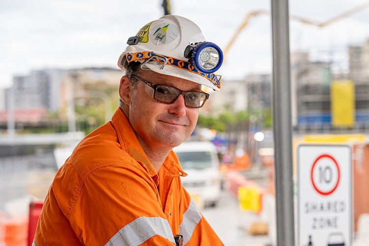 Man in orange high vis shirt and white hard hat