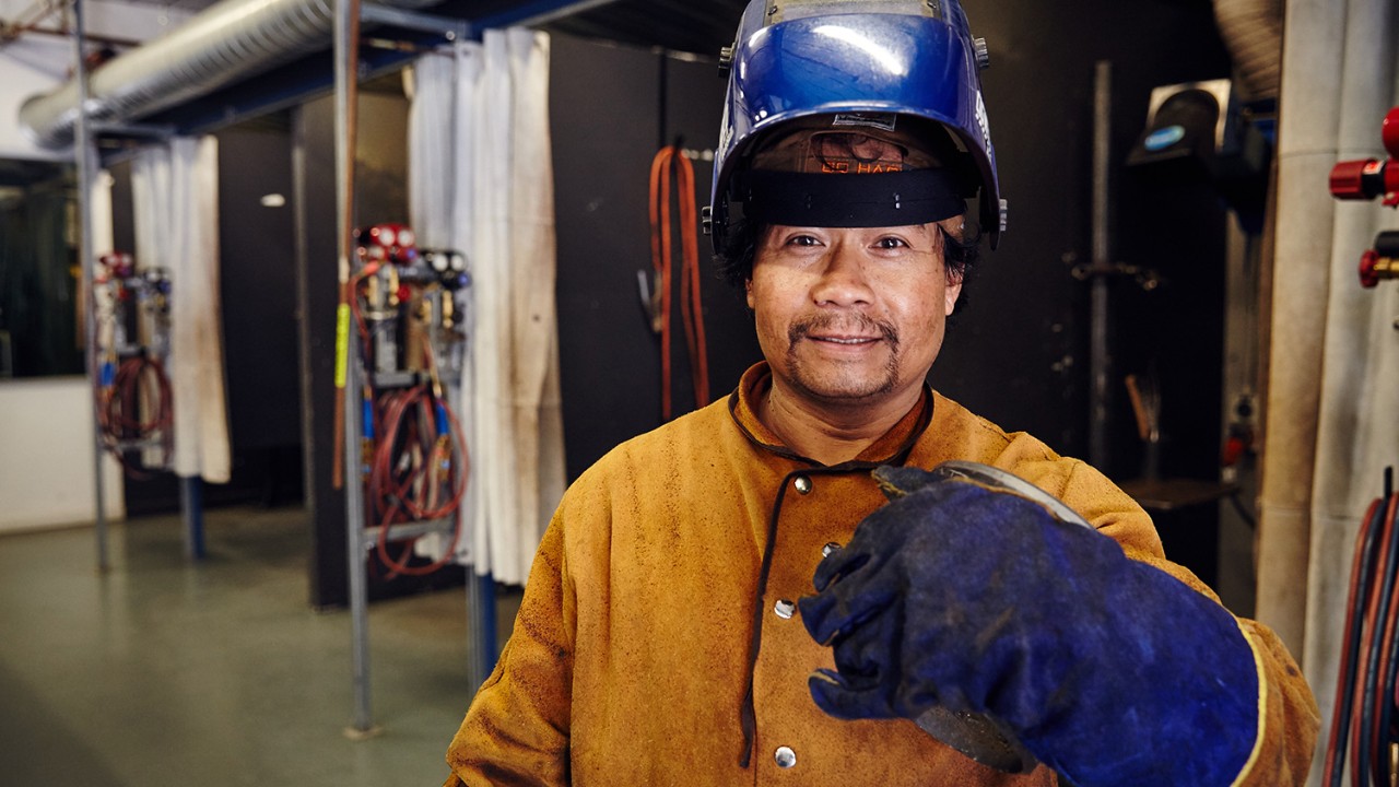 Man dressed in orange welding suit and blue visor
