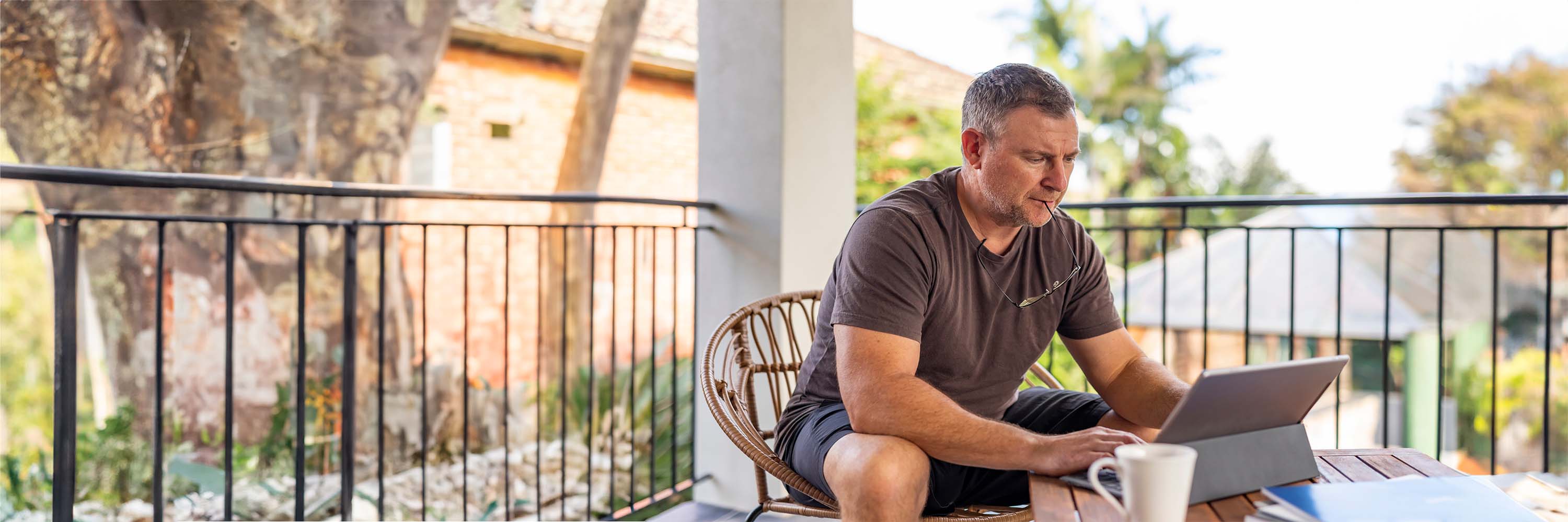 Man on balcony looking at laptop