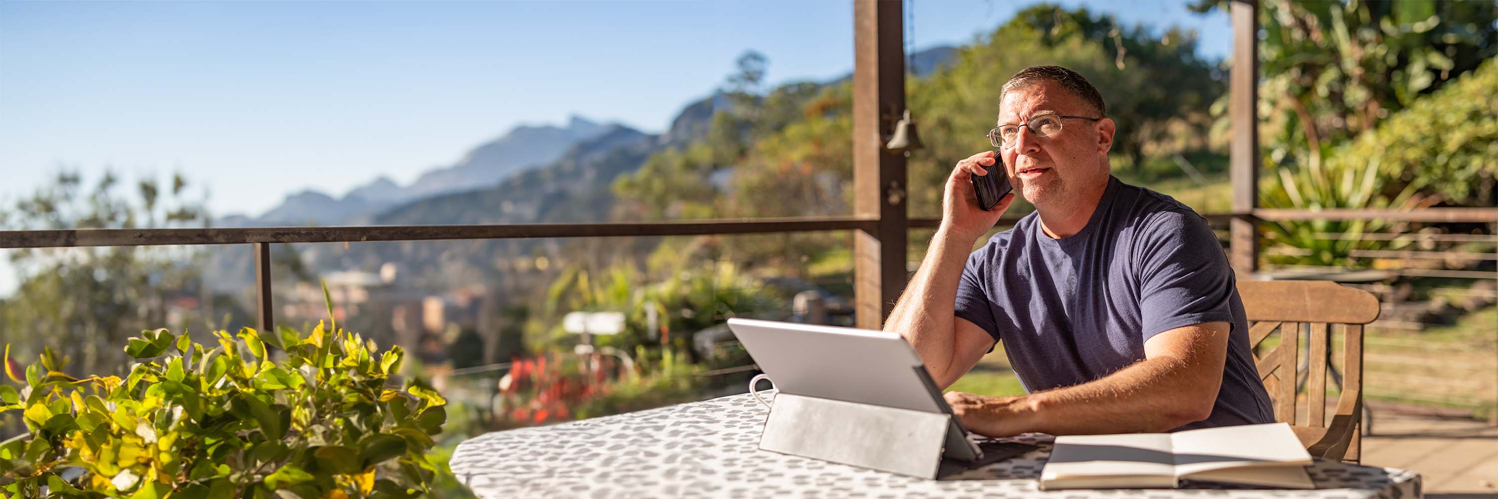 Man on balcony on the phone in front of laptop