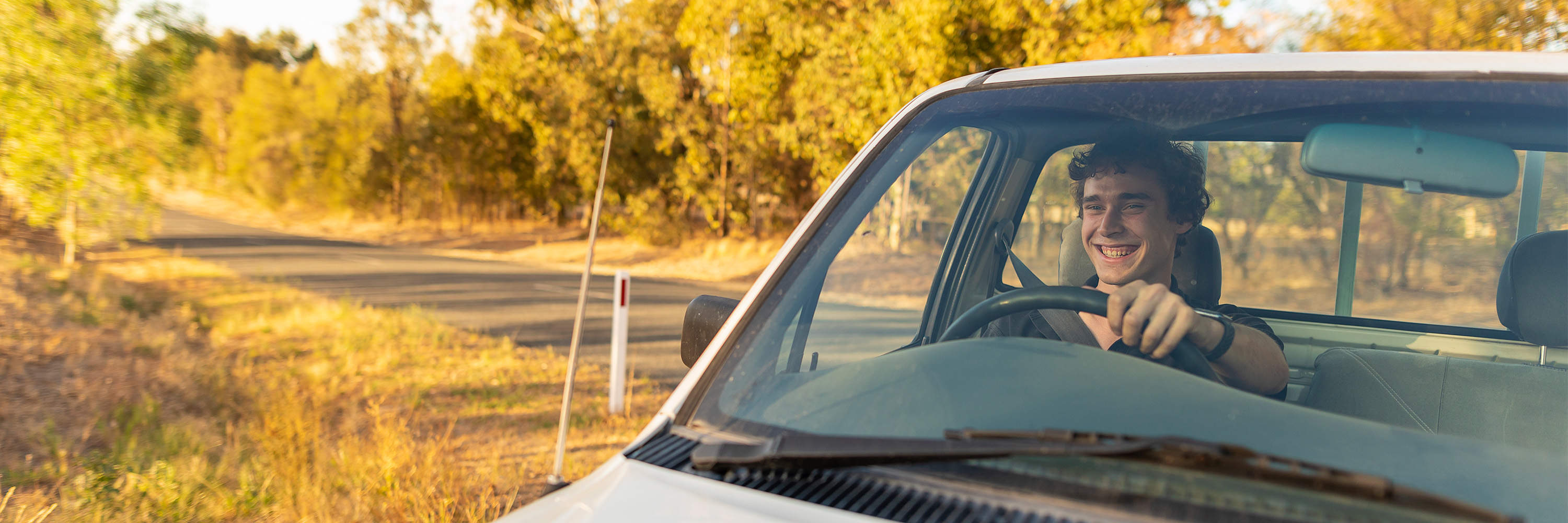 Young man smiling and driving a ute in the outback