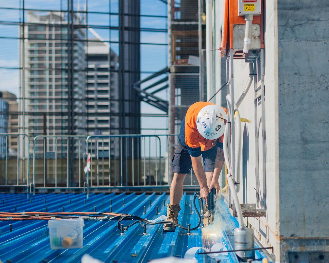 A construction worker on a roof drilling