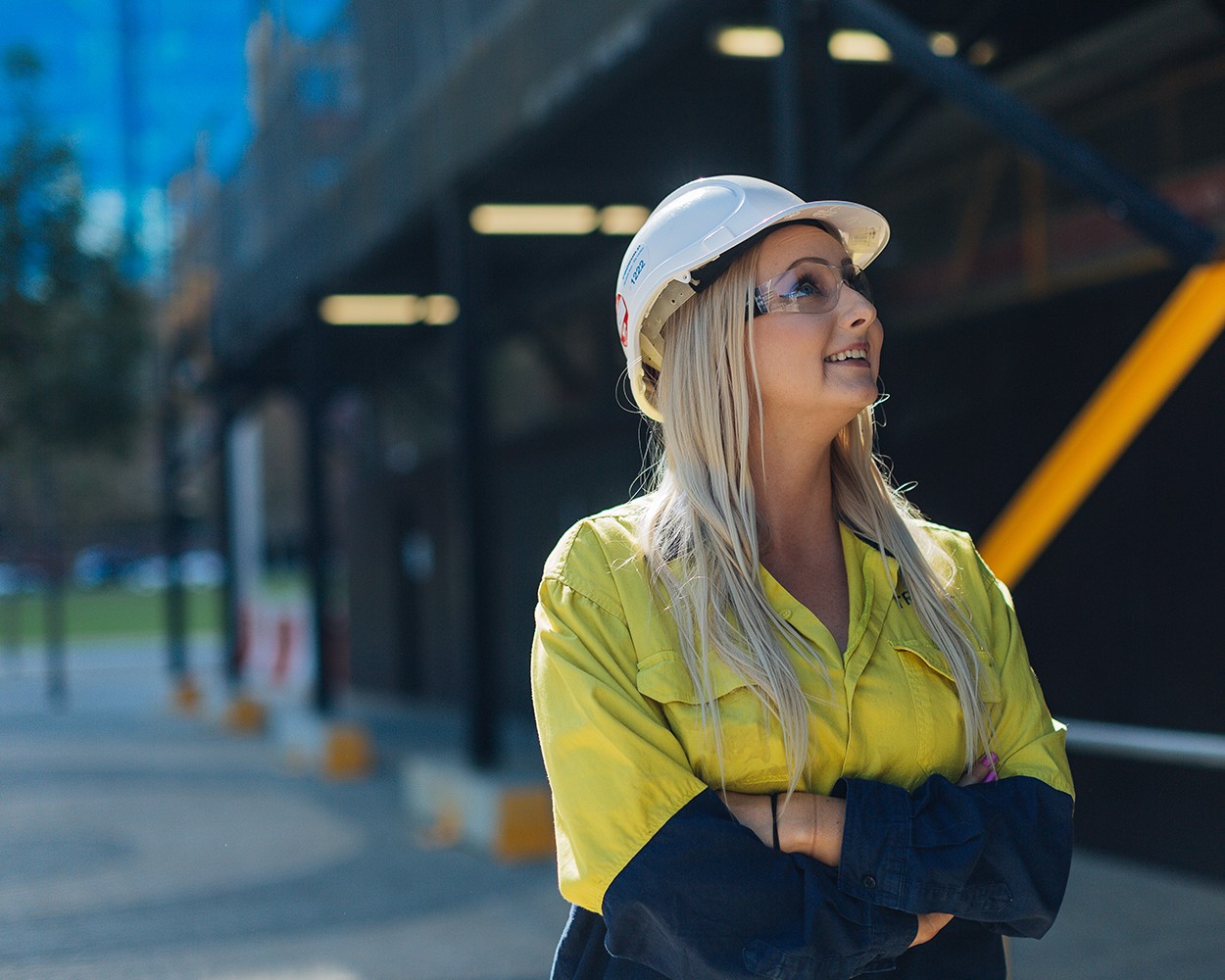 A female tradie looking up towards a building