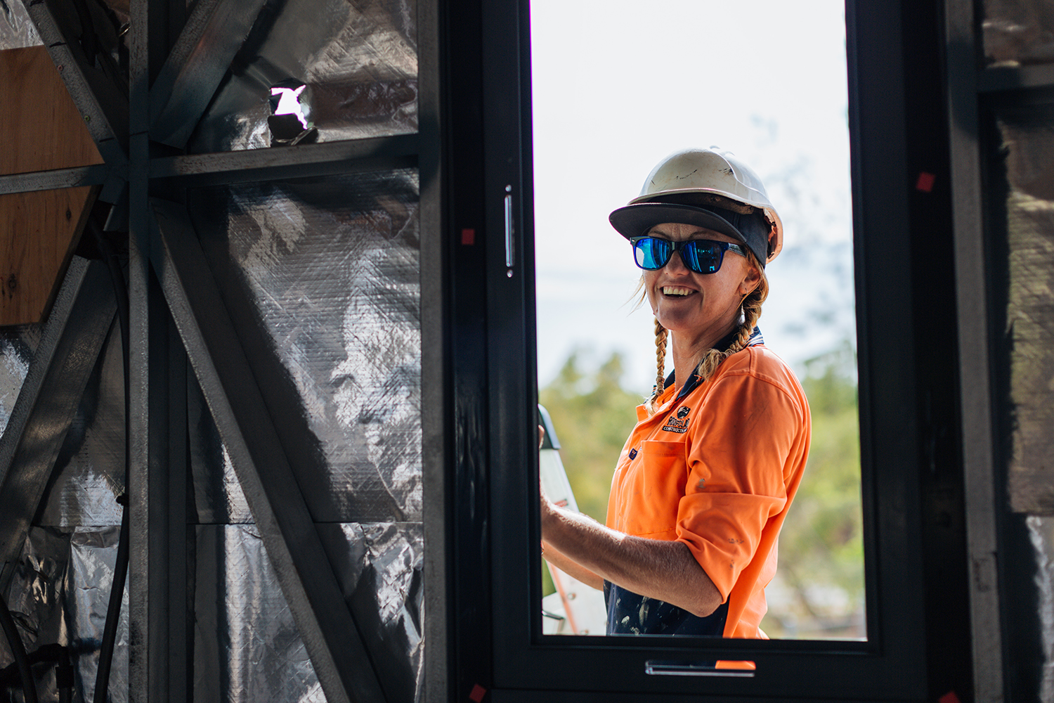 female tradie standing in a window smiling