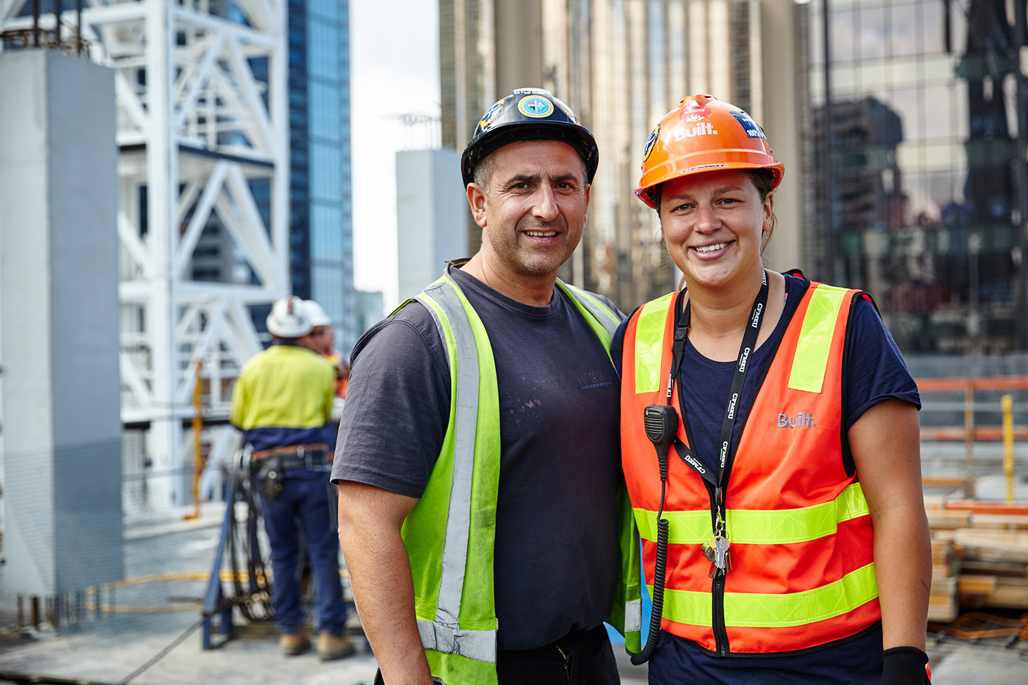 Male and female tradie working on rooftop, smiling