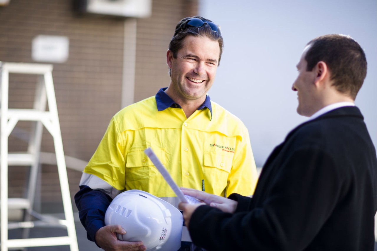 Two men discussing documents in a construction site