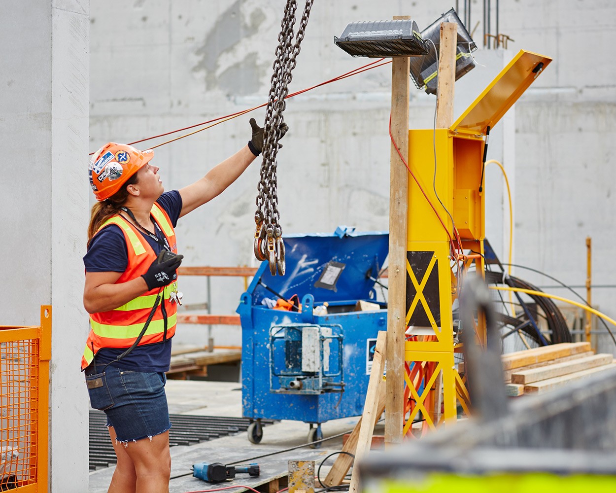 Female construction worker guiding crane